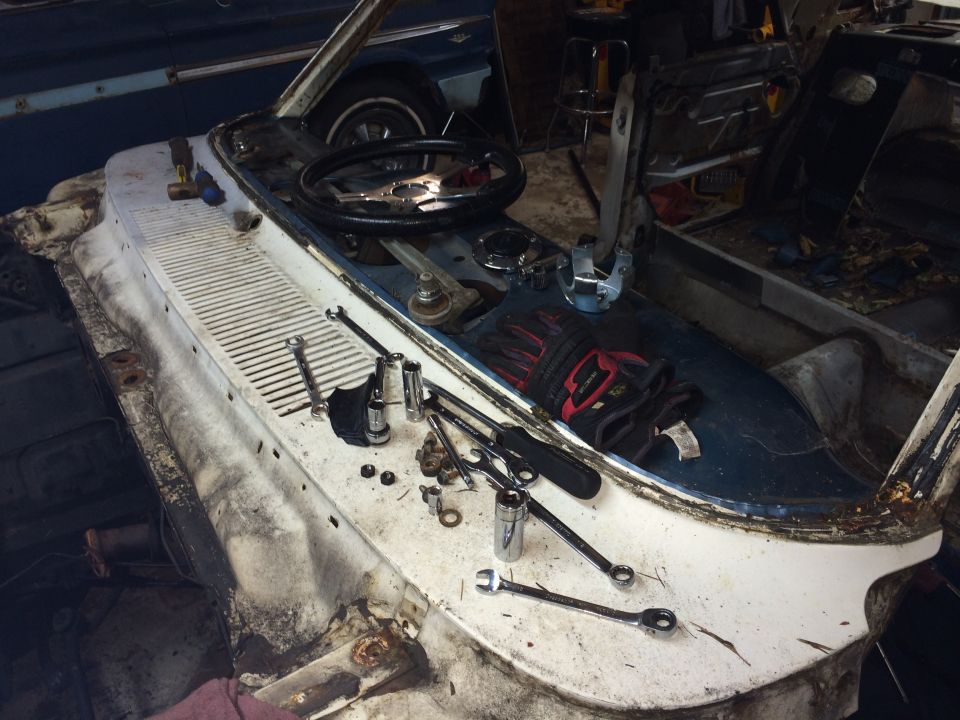1964 Ford Fairlane interior dashboard disassembled with tools and gloves on the dash