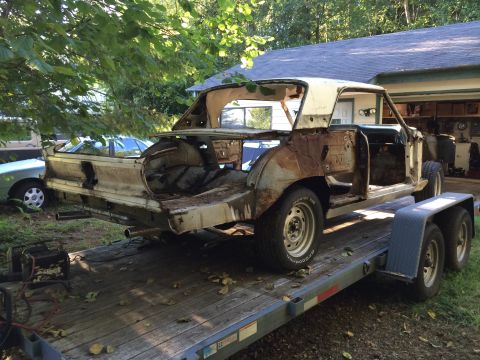1964 Ford Fairlane - This heavily rusted car body is missing many of its original parts and is being transported on a trailer.