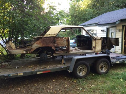 1964 Ford Fairlane - This heavily rusted car body is missing many parts and is being transported on a trailer.