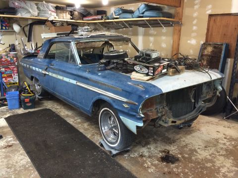 1964 Ford Fairlane - A blue 1964 Ford Fairlane coupe sits in a garage, partially disassembled and awaiting restoration.
