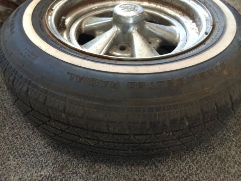 1964 Ford Fairlane - A close-up view of a tire and wheel assembly, showing the tread and a chrome hubcap.