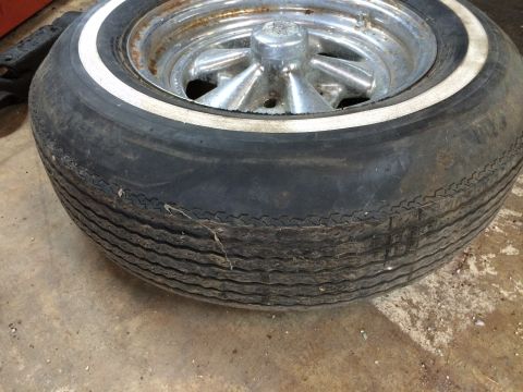 1964 Ford Fairlane - Worn tire with a white sidewall stripe on a chrome rim.