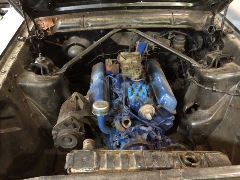 1964 Ford Fairlane - The engine bay of a vehicle, showing the engine, carburetor, and radiator, with signs of rust on the inner fender.