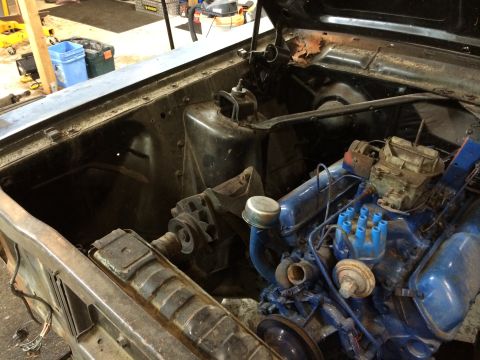 1964 Ford Fairlane - The engine bay of a 1964 Ford Fairlane, a blue engine and carburetor, is shown in this photograph.