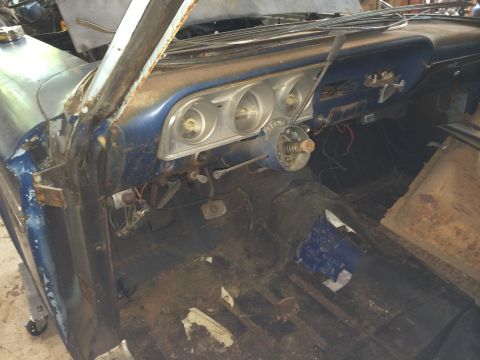 1964 Ford Fairlane - The interior of a 1964 Ford Fairlane shows a blue dashboard with three circular gauges and a removed steering wheel, with a rusty floor and…