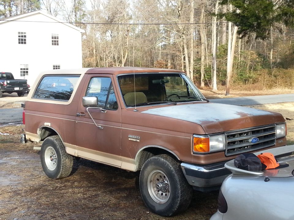 Brown 1991 Ford Bronco, 3q front view. Another truck is visible in the background