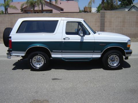 1996 Ford Bronco - This two-tone green and white Ford Bronco is shown from the side with a spare tire mounted on the rear.