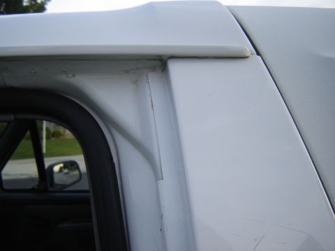 1996 Ford Bronco - Detail shot of the upper door frame and roof trim on a white SUV.