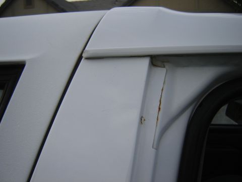 1996 Ford Bronco - Close-up of a white SUV's body panel reveals rust damage around the door jamb.