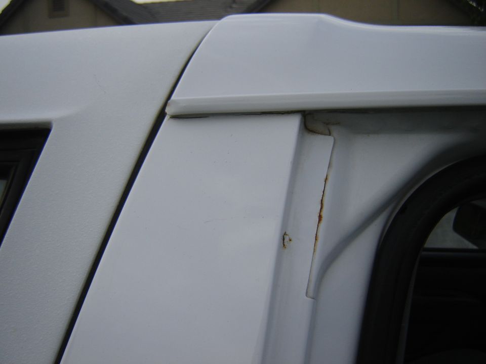 White SUV body panel showing rust near the door frame