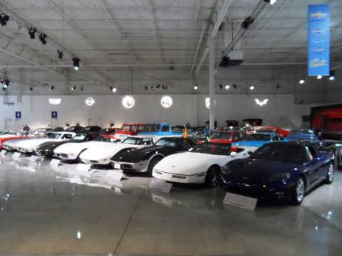 1971 Ford Ranchero - A collection of vehicles, including several Corvettes, are displayed indoors under bright lighting.