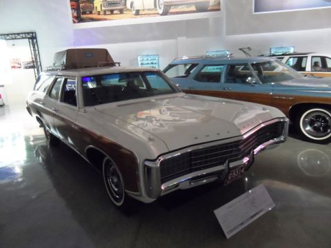 1971 Ford Ranchero - A white station wagon with wood paneling and a roof rack is displayed in a museum next to a blue station wagon.