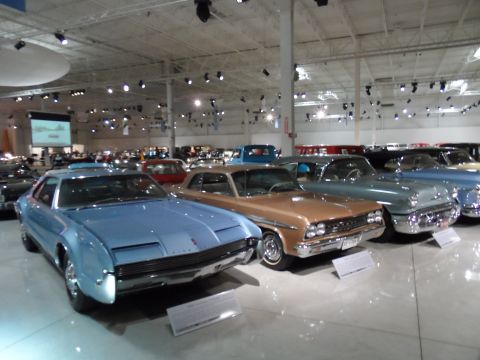 1971 Ford Ranchero - Several classic cars are on display in a museum, including a light blue coupe and a tan coupe.