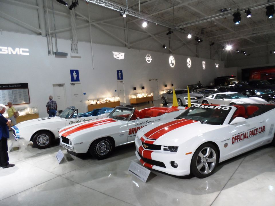 White Chevrolet Camaros with red stripes, one labeled 'Official Pace Car', displayed in a museum