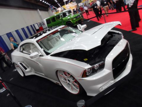 1971 Ford Ranchero - A customized white Dodge Charger is displayed with its hood open, alongside a green SUV at an indoor event.