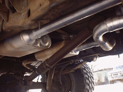 1988 Ford Bronco - Custom exhaust system parts visible on the underside of a vehicle, including pipes and a muffler.