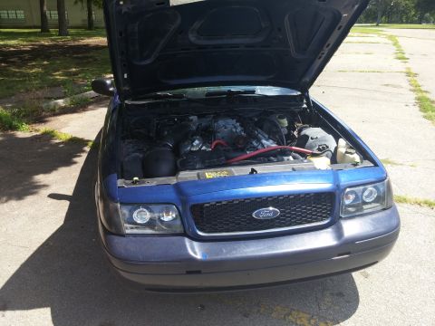 2000 Mercury Grand Marquis - Front view of a blue sedan with its hood open, revealing the engine compartment and a Ford grille.