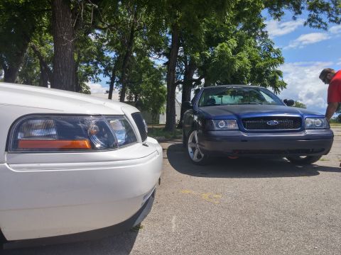 2000 Mercury Grand Marquis - Two Ford Crown Victorias parked side-by-side on a sunny day.