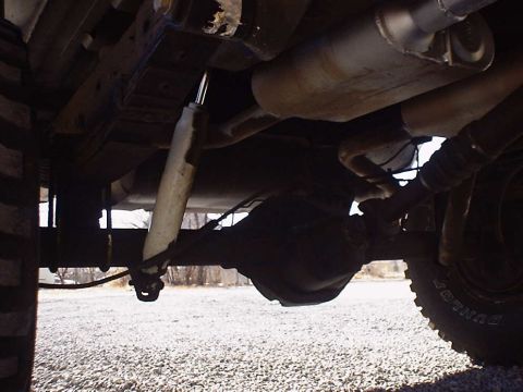 1988 Ford Bronco - The photo shows the rear axle and suspension components of a vehicle, including a shock absorber and exhaust pipes.