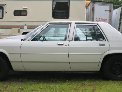 1991 Ford LTD Crown Victoria - Side profile of a white sedan, possibly a Ford Crown Victoria, with black wheels.