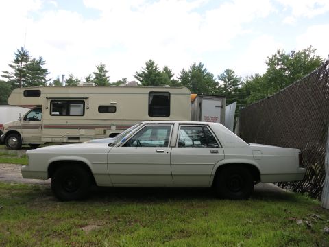 1991 Ford LTD Crown Victoria - A white 1991 Ford Crown Victoria LTD sedan is parked next to an RV in a grassy area.