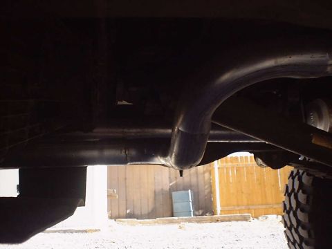 1988 Ford Bronco - Underside view of a vehicle's exhaust system, with tire tread visible on the right side.