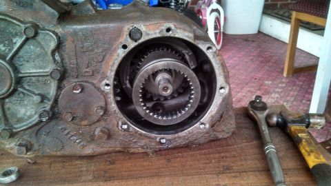 1979 Ford Bronco - Close-up of a disassembled transfer case, showing internal gears and surrounding housing, with tools nearby.