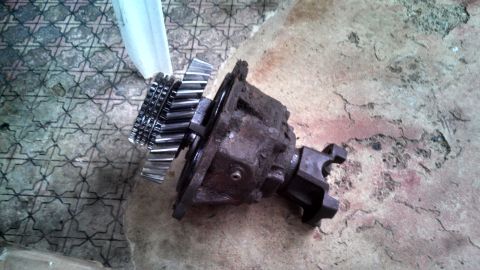 1979 Ford Bronco - Transfer case part with gears and yoke on a concrete floor.