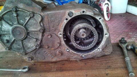 1979 Ford Bronco - A disassembled transfer case sits on a wooden surface, showing its internal gears and housing.
