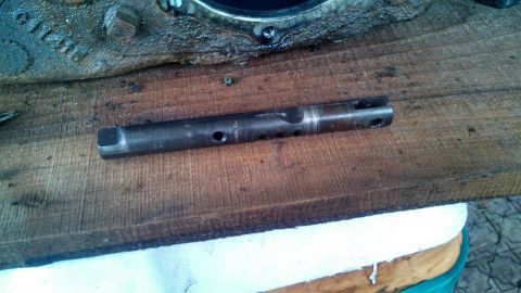 1979 Ford Bronco - A metal shaft with holes and a split end rests on a wooden surface.