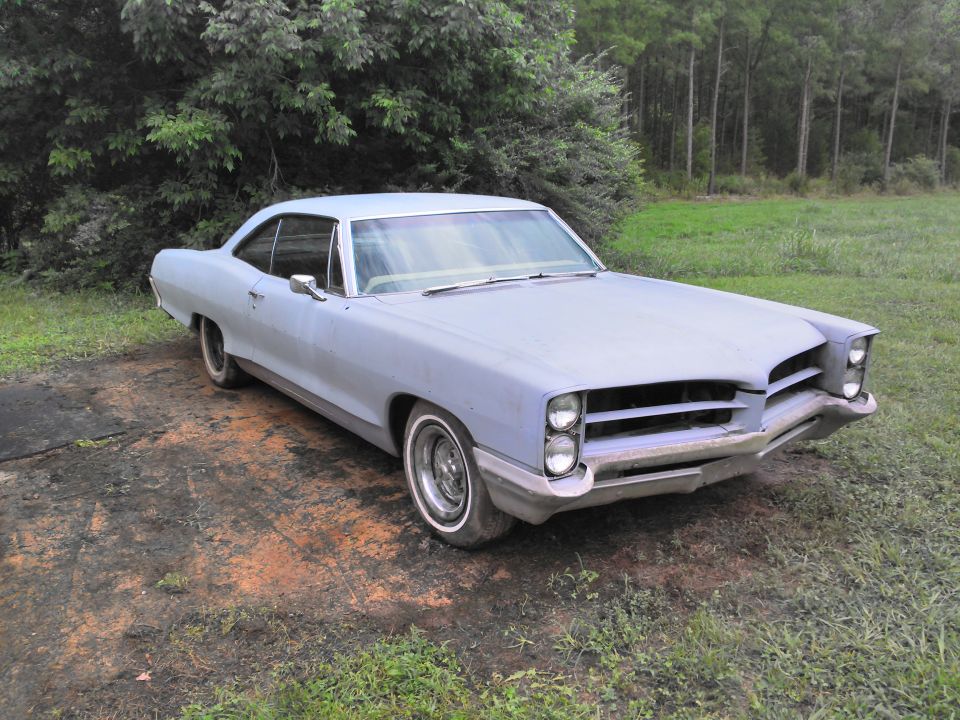 Light blue 1966 Pontiac Catalina coupe, primer finish, parked on dirt and grass