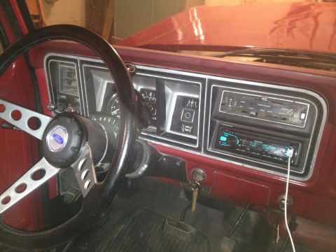 1978 Ford Bronco - Interior view of a red 1978 Ford Bronco dashboard, showing the steering wheel, instrument cluster, and radio.