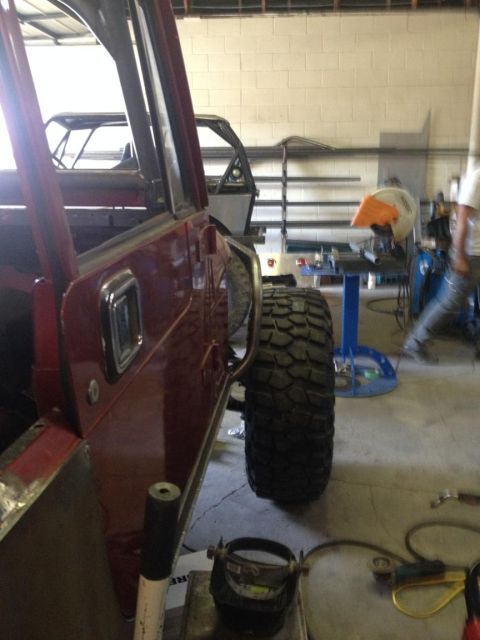 1985 Jeep CJ7 - Workshop scene with a red Jeep CJ-series and another Jeep tub in the background.