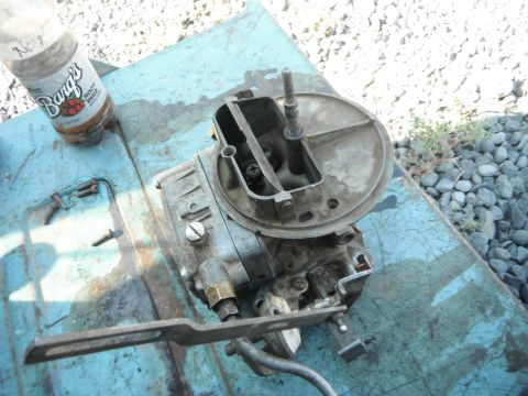 1972 International Scout II - A carburetor sits on a blue surface next to a bottle of Barg's Root Beer.