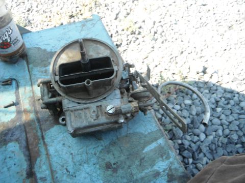 1972 International Scout II - A carburetor sits on a weathered blue surface, with a bottle of root beer nearby.
