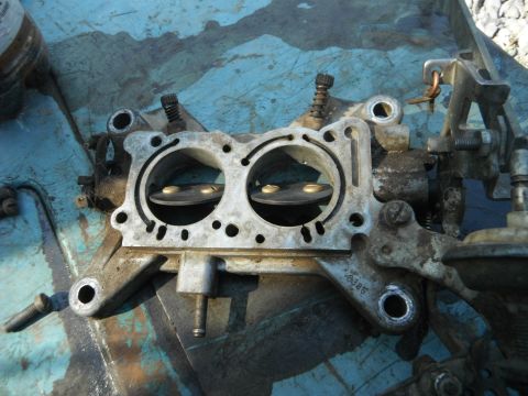 1972 International Scout II - A carburetor, likely from a vintage vehicle, is shown in detail, highlighting its internal components and external linkages.