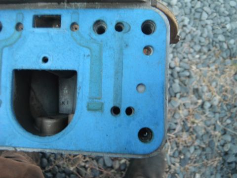 1972 International Scout II - A close-up view of a blue carburetor base plate, showing internal passages and mounting holes.