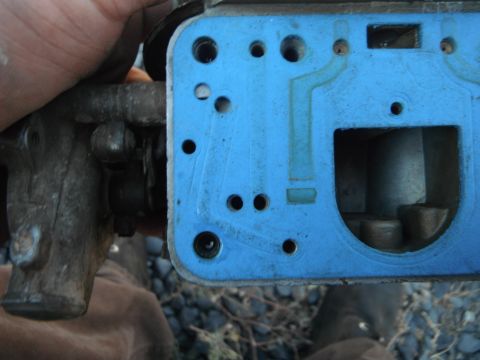 1972 International Scout II - Close-up view of a blue gasket on a carburetor part, showing various holes and internal components.