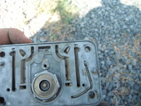 1972 International Scout II - This is a close-up view of a carburetor's base plate, showing its intricate internal channels and a central brass component.