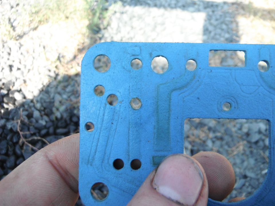 Close-up of a blue carburetor gasket with many holes and channels