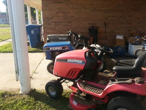 2002 Ford Expedition - Two lawn mowers, a red Snapper and a blue Ford, are parked side-by-side outdoors.