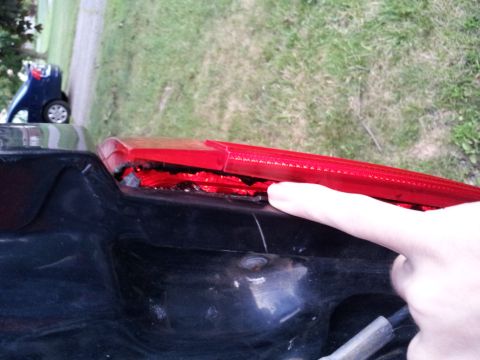 1995 Ford Bronco - Close-up of a damaged red taillight assembly, with a finger pointing to the broken area.