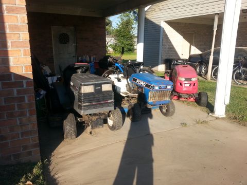 2002 Ford Expedition - A collection of lawn tractors, including a blue Ford model, are stored under a covered area.