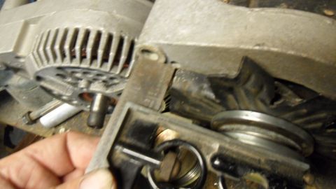 1972 Ford Ranchero - A close-up view of an alternator part, with a hand holding a tool near the internal components.