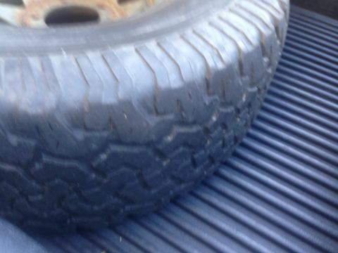 1986 Ford Bronco - Spare tire positioned on a black ribbed truck bed liner.