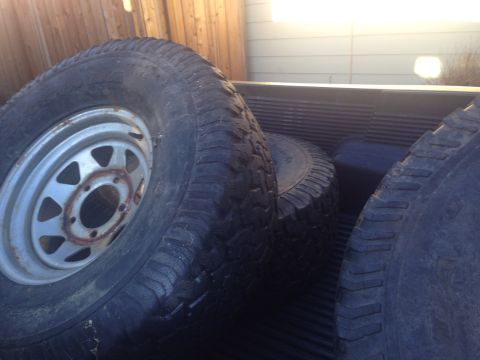 1986 Ford Bronco - Several tires are stacked in the cargo area of a vehicle.