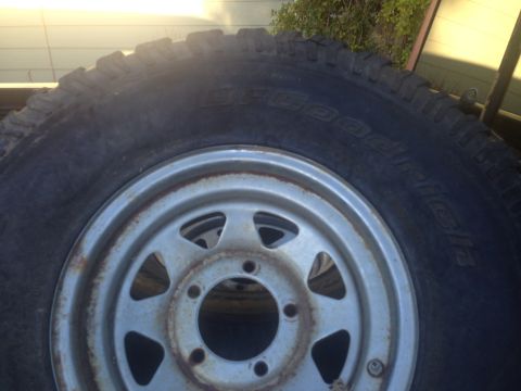 1986 Ford Bronco - Close-up of a BFGoodrich All-Terrain T/A tire mounted on a steel wheel, showing tread detail and rust on the rim.
