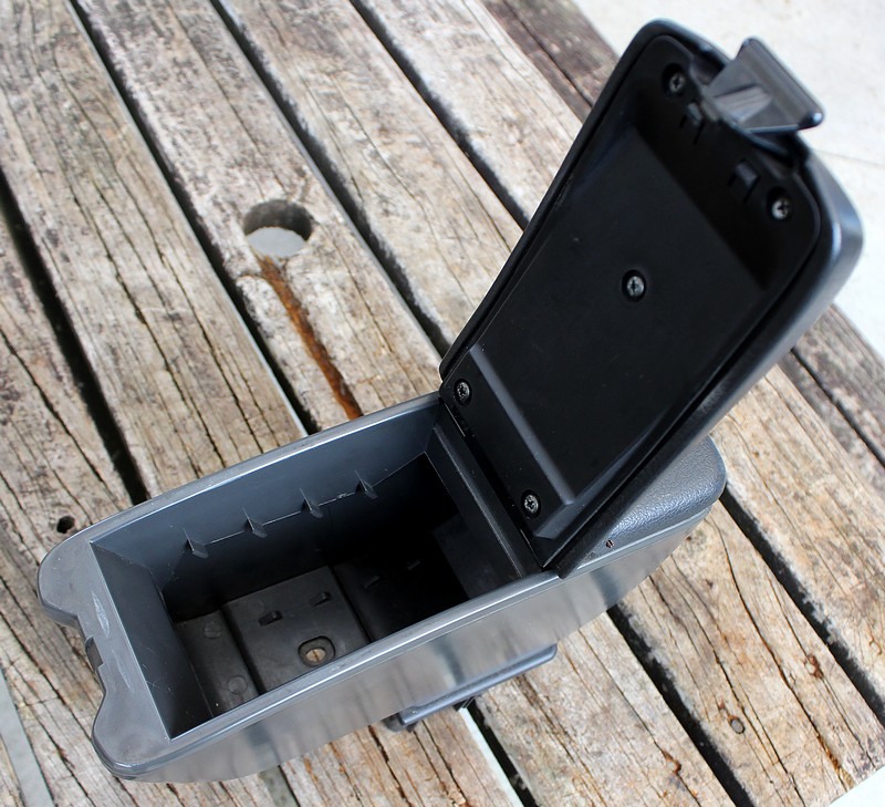 Open car armrest storage compartment on a wooden table