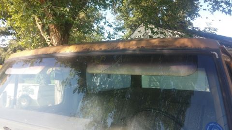 1979 Ford Bronco - Close-up of a vehicle's rusted roofline and interior sun visors.