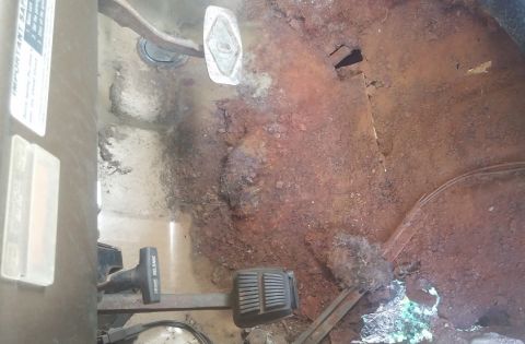 1979 Ford Bronco - Floor pan shows significant rust damage and wear around the pedals and lever.